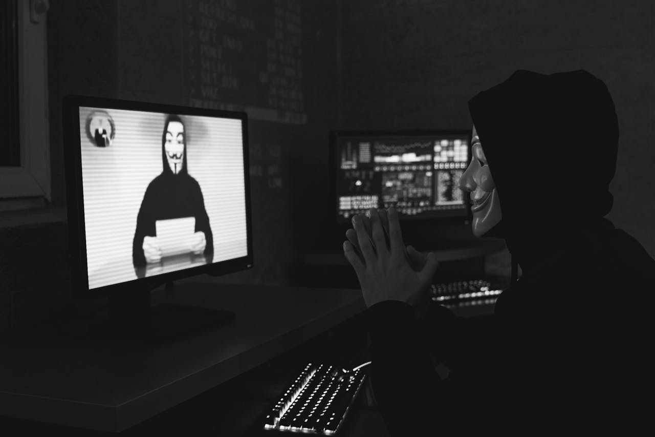 Monochrome image of a masked hacker on a video call, showcasing cyber security themes.